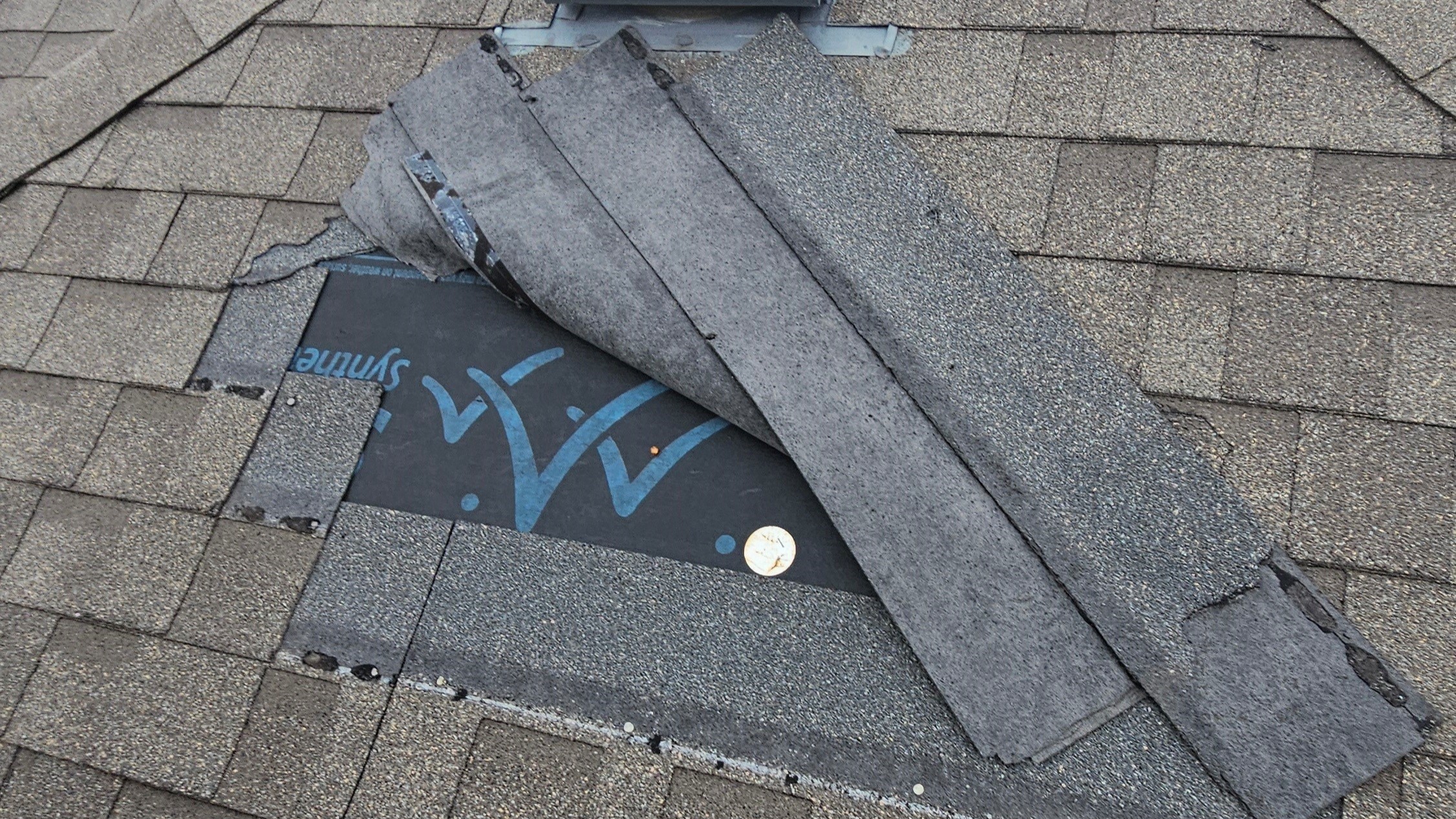 A closeup of damaged shingles on a roof in the Greater Austin area of Texas before Freetail Roofing repairs them.